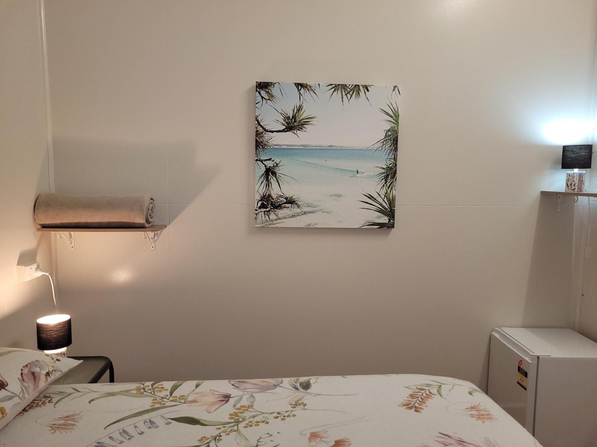 Travellers Paradise Кернс Екстериор снимка A photograph of a bedroom with a bed, a nightstand, a lamp, a painting, and a television